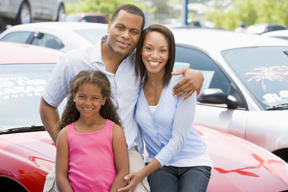 Happy family in front of a car covered by Thompson Durkee Insurance